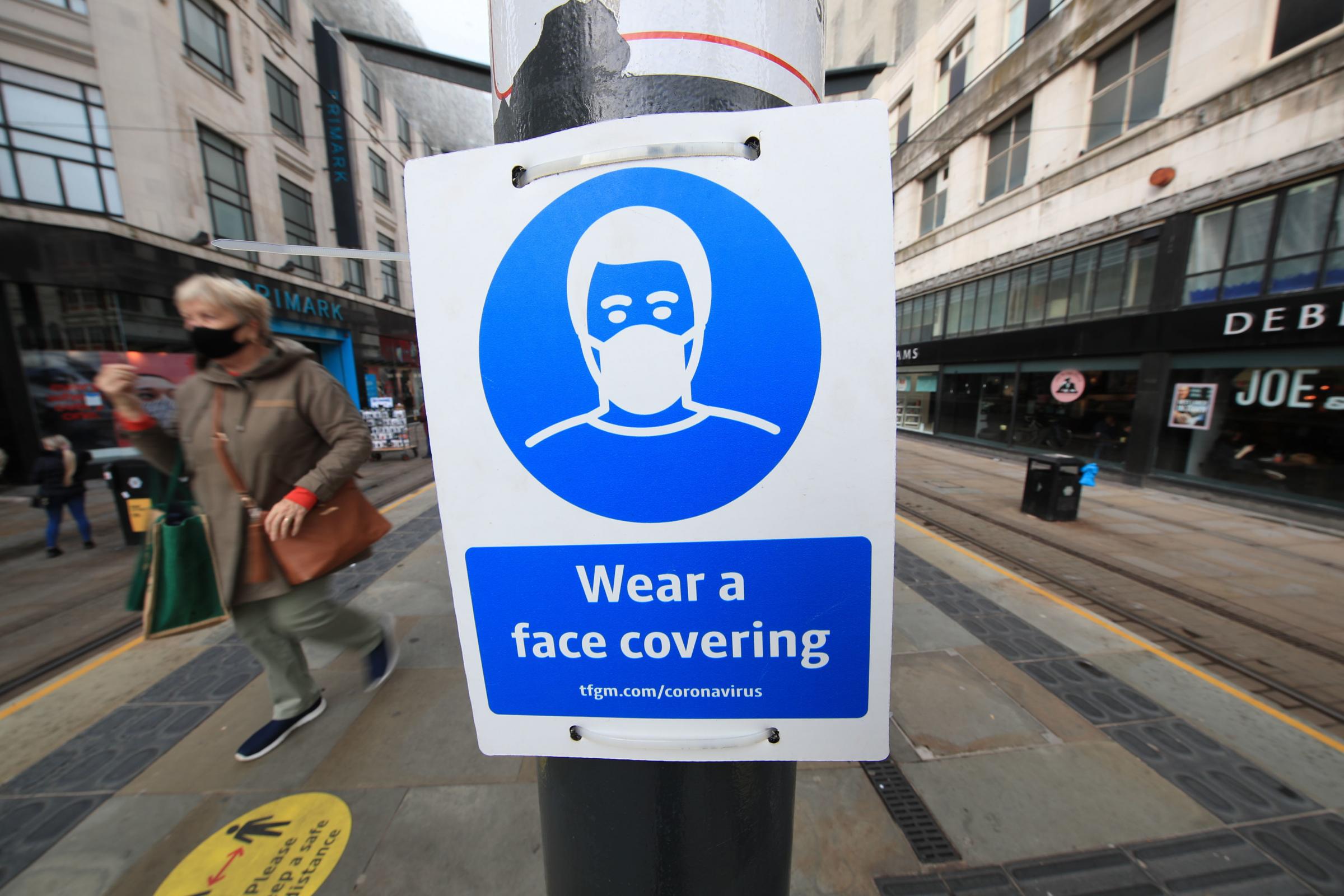 A sign advising on wearing face coverings at a tram stop in Manchester. Cities in northern England and other areas suffering a surge in Covid-19 cases may have pubs and restaurants temporarily closed to combat the spread of the virus..